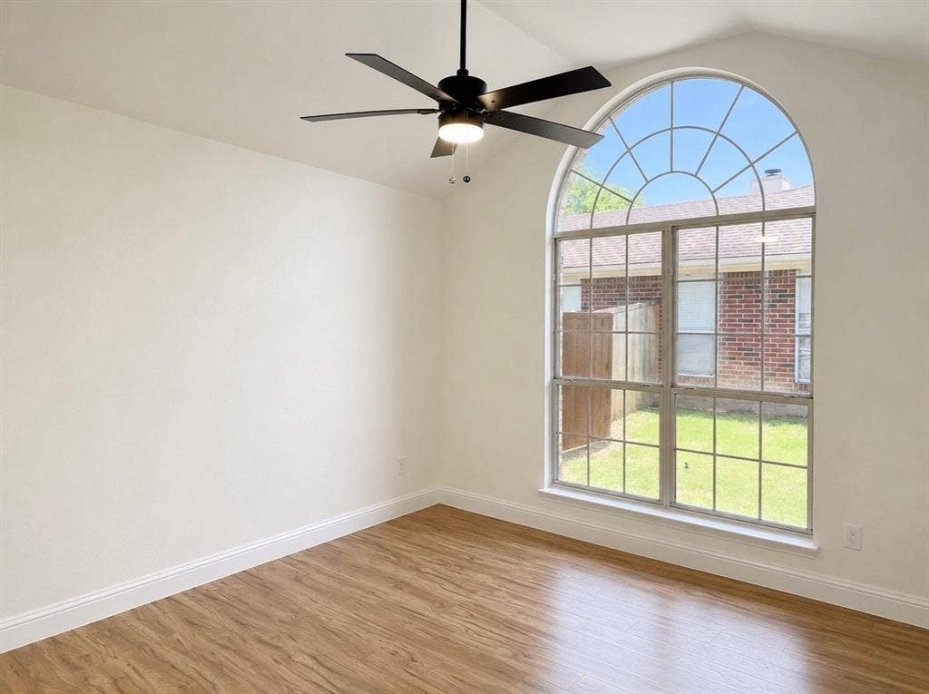 2400 Waterloo Lane, Mesquite, TX 75181 Vaulted ceilings, wood-finish flooring, large arched window with muntin detailing, and a multi-blade ceiling fan with integrated lighting