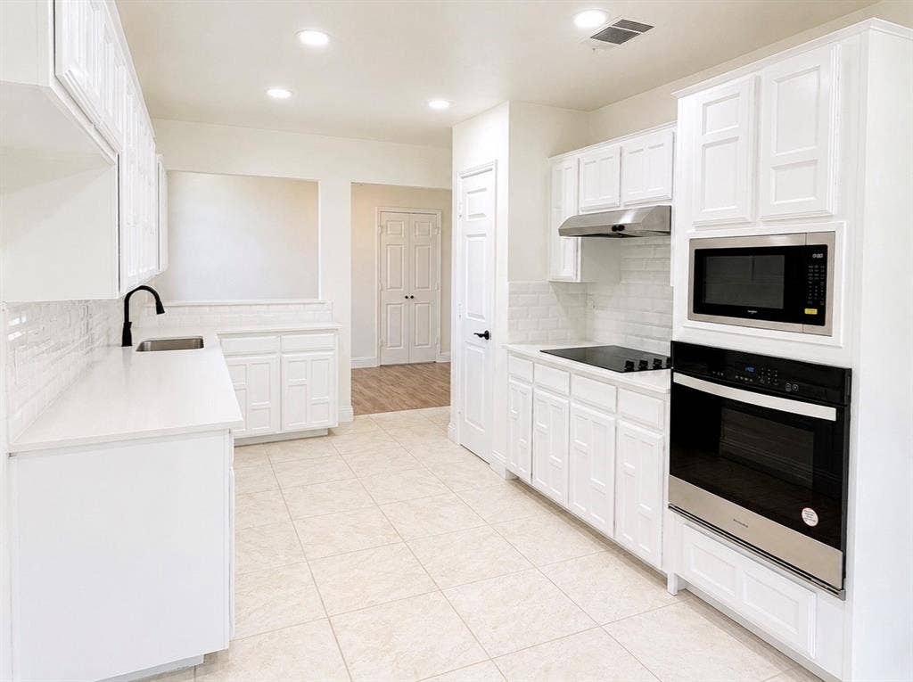 2400 Waterloo Lane, Mesquite, TX 75181 Kitchen featuring white cabinetry with geometric panel detailing, solid surface countertops, a white subway tile backsplash, recessed lighting, and a built-in stainless steel wall oven and microwave combination
