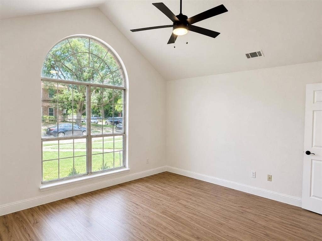 2400 Waterloo Lane, Mesquite, TX 75181 Vaulted ceiling featuring a matte black ceiling fan, wood-finish flooring, and an arched window