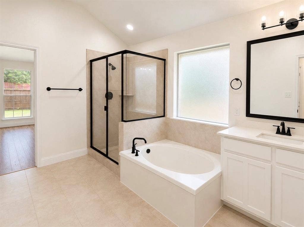 2400 Waterloo Lane, Mesquite, TX 75181 Bathroom featuring a soaking tub, separate glass-enclosed shower with matte black fixtures, vanity with quartz countertop, and framed mirror