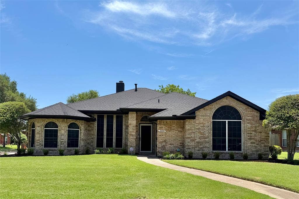 2400 Waterloo Lane, Mesquite, TX 75181 Single-story brick exterior featuring a multi-gabled roofline, prominent arched windows, and a paved walkway