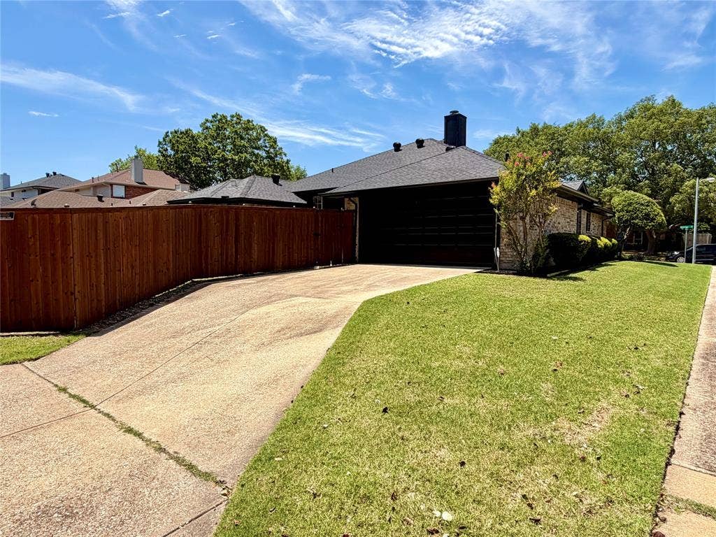 2400 Waterloo Lane, Mesquite, TX 75181 Exterior featuring a brick facade, concrete driveway, attached garage, and vertical wood plank privacy fencing