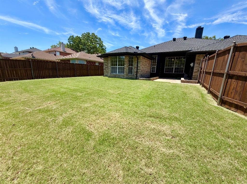 2400 Waterloo Lane, Mesquite, TX 75181 Expansive backyard featuring a sod lawn, perimeter wood privacy fencing, and exterior masonry detailing