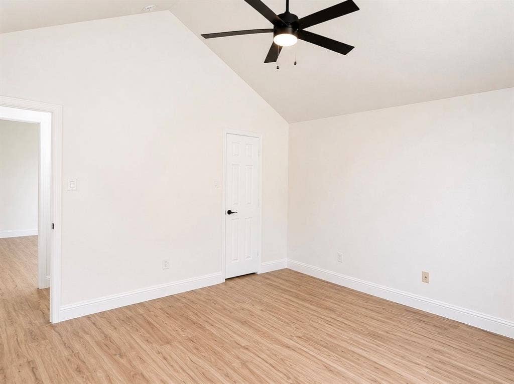 2400 Waterloo Lane, Mesquite, TX 75181 Vaulted ceiling featuring a central matte black six-blade ceiling fan with integrated lighting and wood-finish flooring