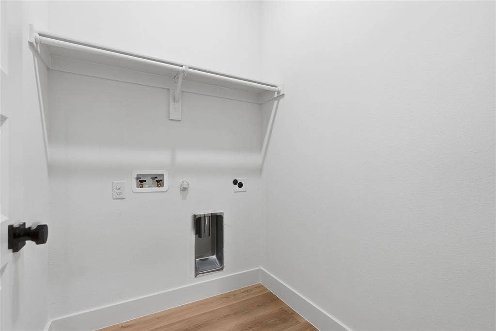 1834 Gallagher Street, Dallas, TX 75212 Laundry utility area featuring wood-finish flooring, a metal recessed drain box, dedicated plumbing connections, and a built-in overhead shelf with an integrated clothing rod