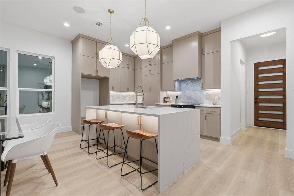 1834 Gallagher Street, Dallas, TX 75212 Kitchen featuring flat-panel cabinetry, quartz waterfall island, stone backsplash, geometric pendant lighting, and wood-finish flooring
