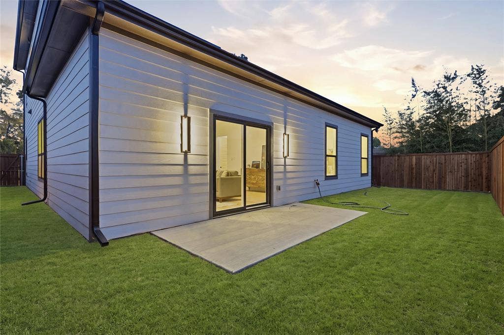 1834 Gallagher Street, Dallas, TX 75212 Horizontal lap siding exterior featuring a concrete patio, sliding glass door, linear wall-mounted outdoor lighting, and wood-panel perimeter fencing