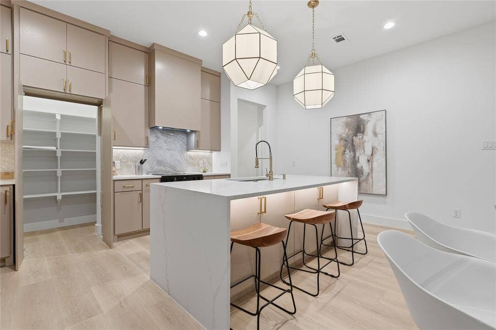 1834 Gallagher Street, Dallas, TX 75212 Kitchen featuring a central island with a waterfall-edge countertop, floor-to-ceiling cabinetry, geometric pendant lighting, walk-in pantry, and wood-finish flooring