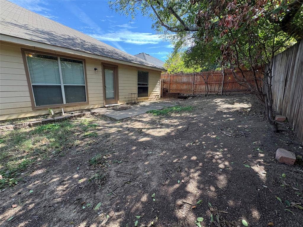 Rear exterior featuring a concrete patio, wood-frame siding, and a wooden privacy fence
