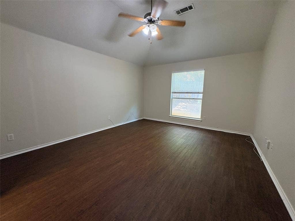 Vaulted ceiling featuring a central five-blade ceiling fan with integrated light fixture and wood-finish flooring