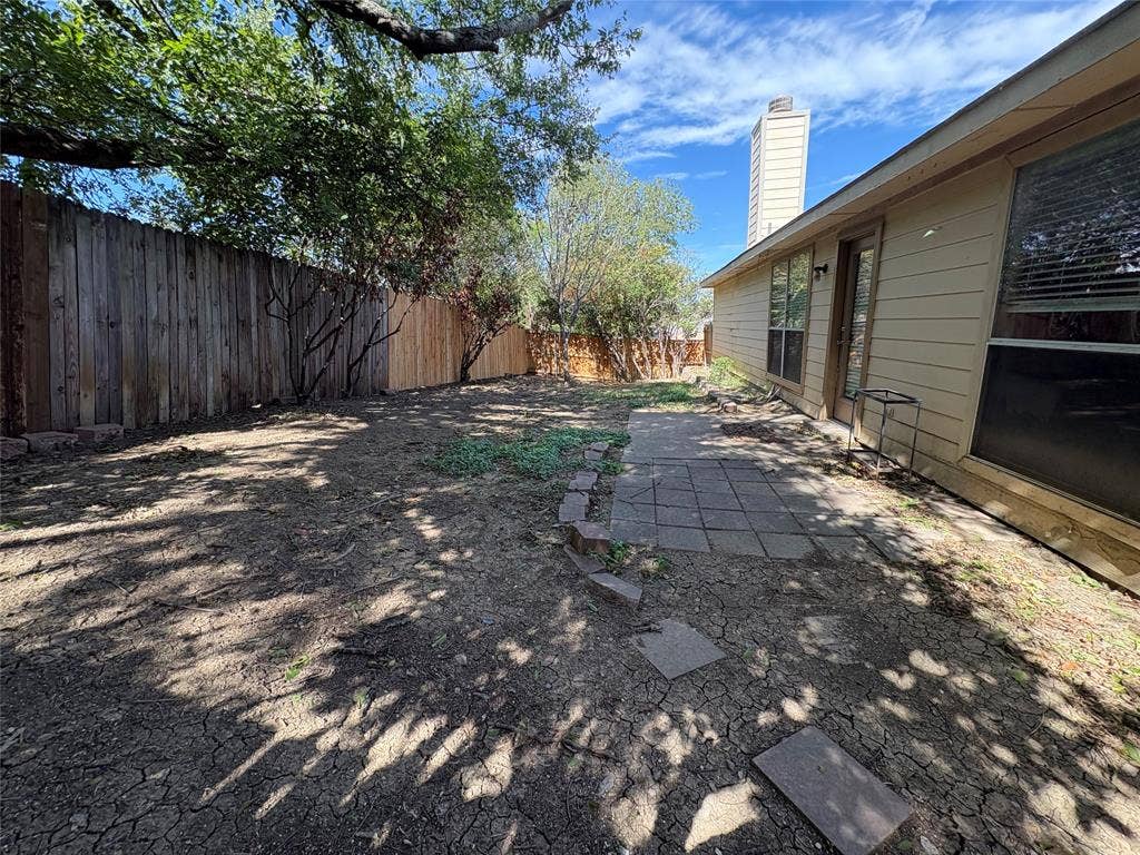 Backyard featuring horizontal siding, a tall chimney, wood privacy fencing, and a paver stone patio