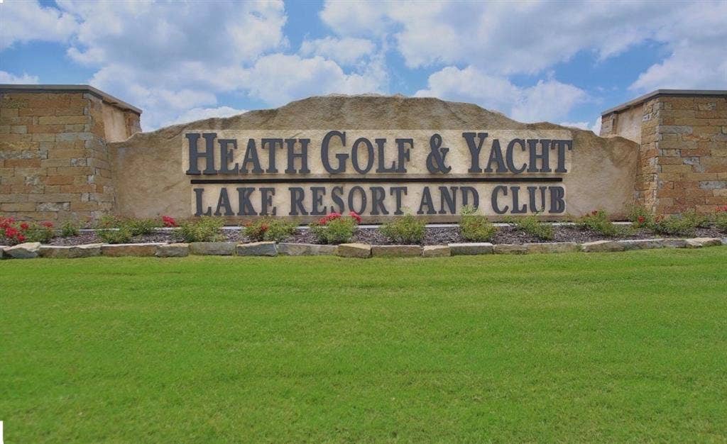 Community signage featuring stone masonry pillars and natural rock facade elements, set against a manicured lawn and landscaping