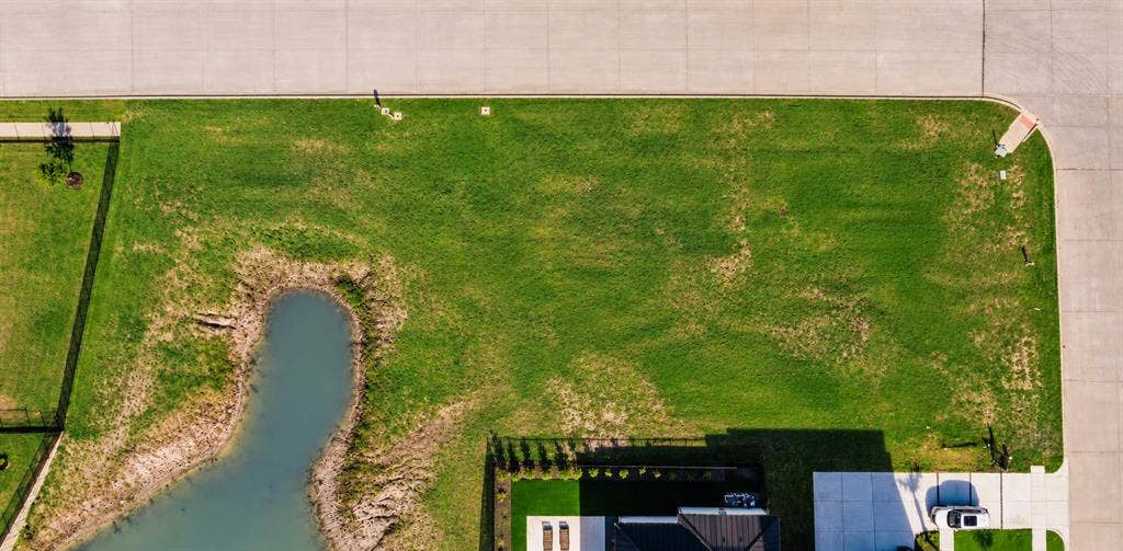 Corner lot featuring an expansive lawn, water feature, and concrete street access