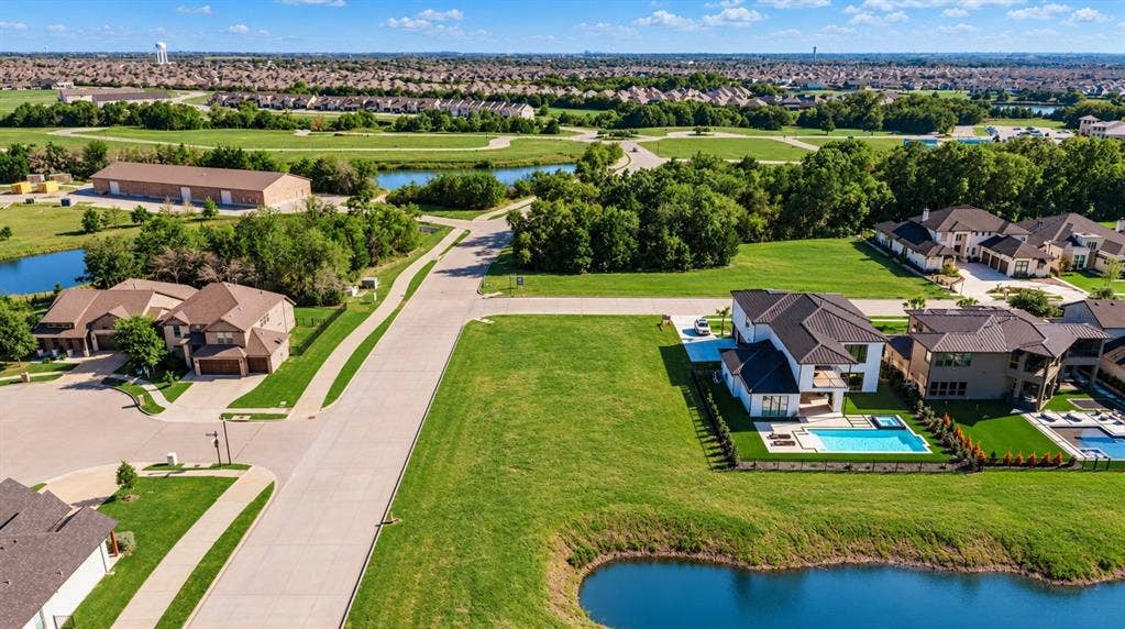 Aerial perspective featuring a residential lot with a swimming pool, integrated spa, and manicured landscaping, situated near a body of water