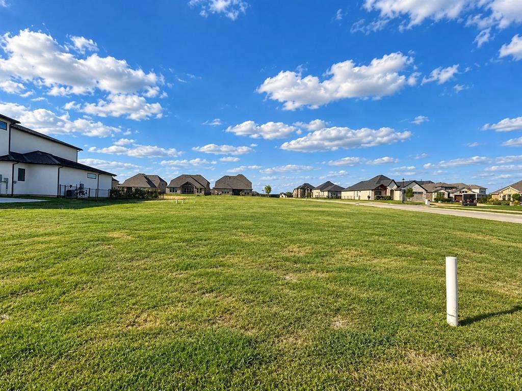 Expansive level lot featuring open green space, paved street access, and utility infrastructure