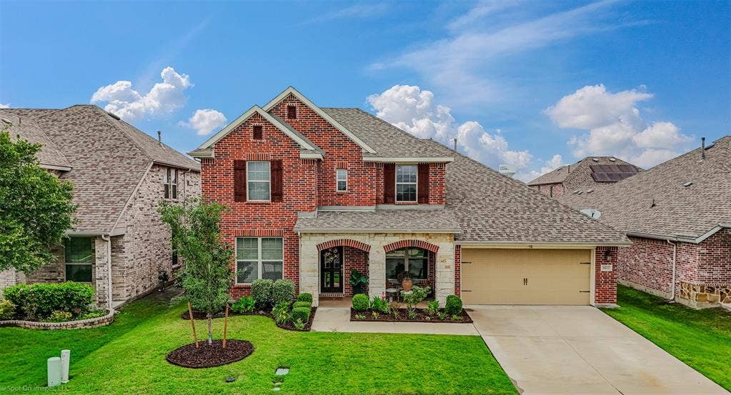 1612 Village Creek Drive, Forney, TX 75126 Traditional home featuring brick siding, a shingled roof, an attached garage, concrete driveway, and a front lawn