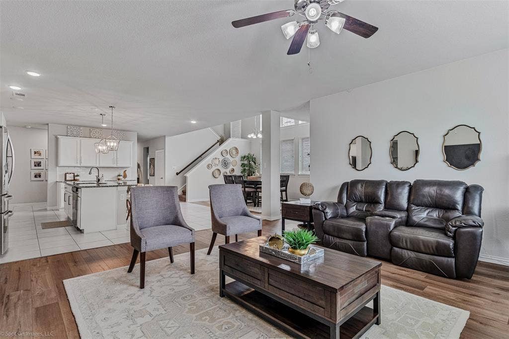 1612 Village Creek Drive, Forney, TX 75126 Living room featuring stairway, ceiling fan, a chandelier, light wood-style floors, and recessed lighting
