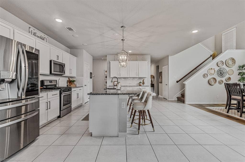 1612 Village Creek Drive, Forney, TX 75126 Kitchen with stainless steel appliances, a kitchen breakfast bar, recessed lighting, decorative backsplash, and dark stone counters
