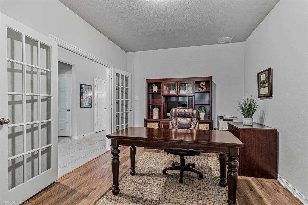 1612 Village Creek Drive, Forney, TX 75126 Home office with french doors, wood finished floors, and a textured ceiling