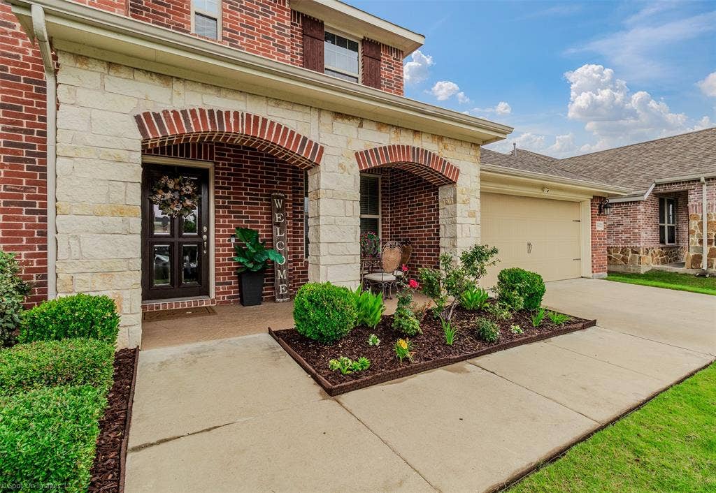 1612 Village Creek Drive, Forney, TX 75126 Entrance to property with an attached garage, brick siding, concrete driveway, and stone siding