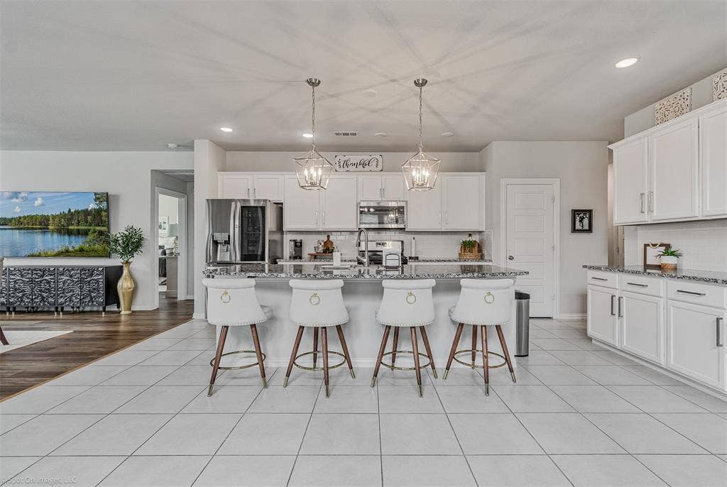 1612 Village Creek Drive, Forney, TX 75126 Kitchen featuring stainless steel appliances, decorative backsplash, a kitchen breakfast bar, recessed lighting, and white cabinets