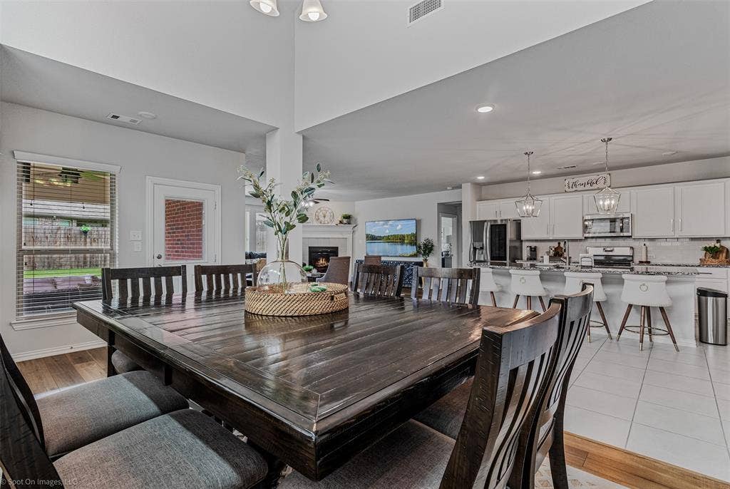 1612 Village Creek Drive, Forney, TX 75126 Dining space featuring healthy amount of natural light, a warm lit fireplace, recessed lighting, a chandelier, and light wood-type flooring