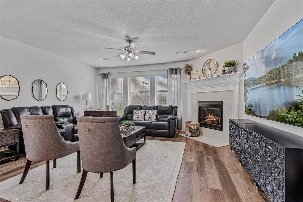 1612 Village Creek Drive, Forney, TX 75126 Living area with a fireplace, a ceiling fan, wood finished floors, and a textured ceiling