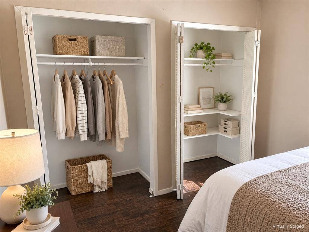 Dual closets featuring white accordion-style doors, interior shelving, and hanging rods over wood-finish flooring