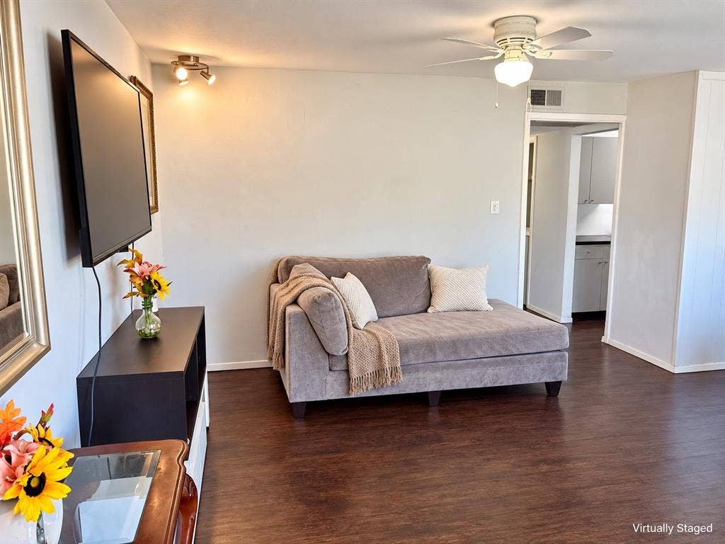 Wood-finish flooring, ceiling fan with integrated lighting, and dual-bulb wall-mounted directional track lighting