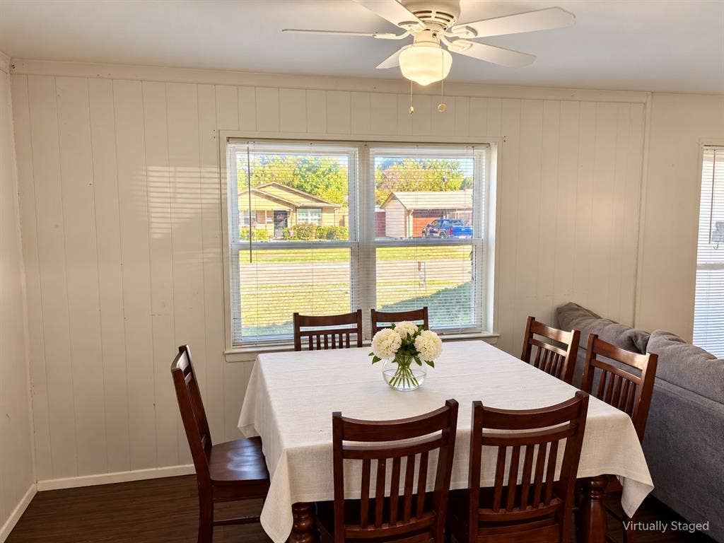 Interior space featuring wood-finish flooring, vertical paneling, double-pane windows, and a ceiling fan with integrated lighting