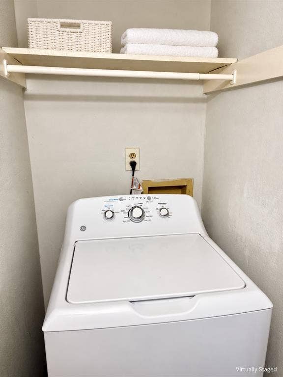 Laundry alcove featuring a top-load washer, a fixed upper storage shelf, and a white closet rod