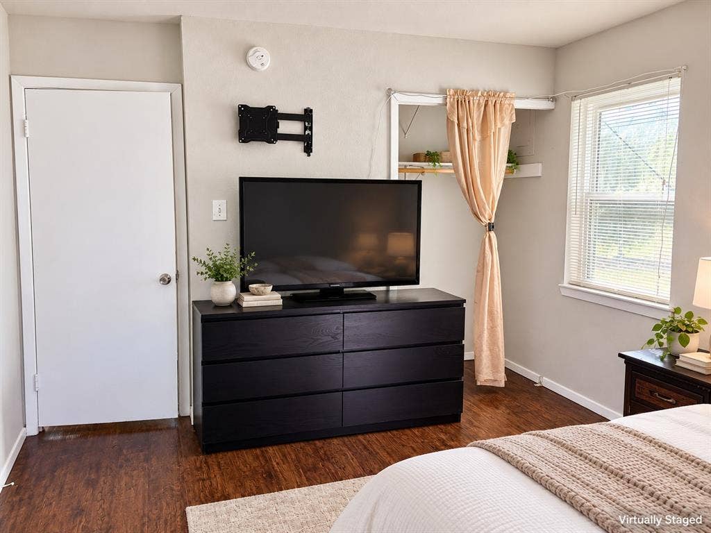 Wood-finish flooring, neutral wall tones, single-hung window with blinds, and built-in closet shelving