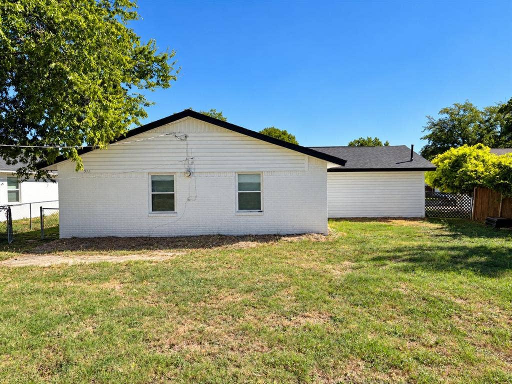Exterior featuring white painted brick and horizontal siding, dark-toned roof shingles, and a large open lawn