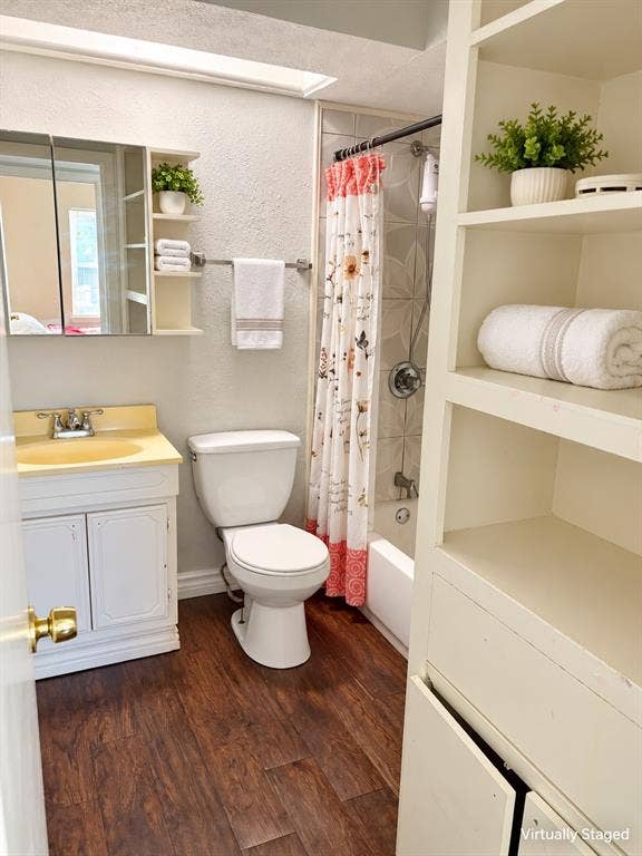 Bathroom featuring wood-finish flooring, built-in shelving unit, mirrored medicine cabinet, and a tub-shower combination with decorative wall tile