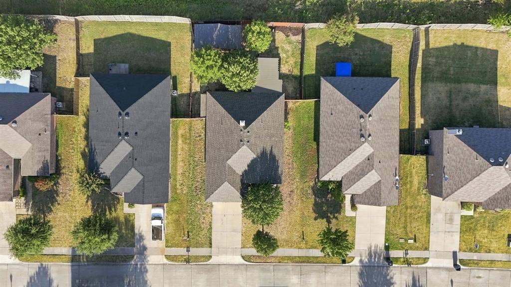 Aerial perspective of residential lots featuring paved driveways, hipped roofs, and established landscaping