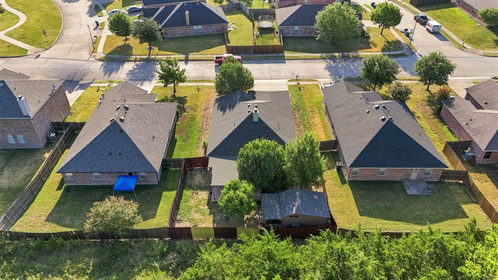 Aerial perspective of a residential lot featuring a detached storage shed, mature perimeter trees, and a wooden privacy fence