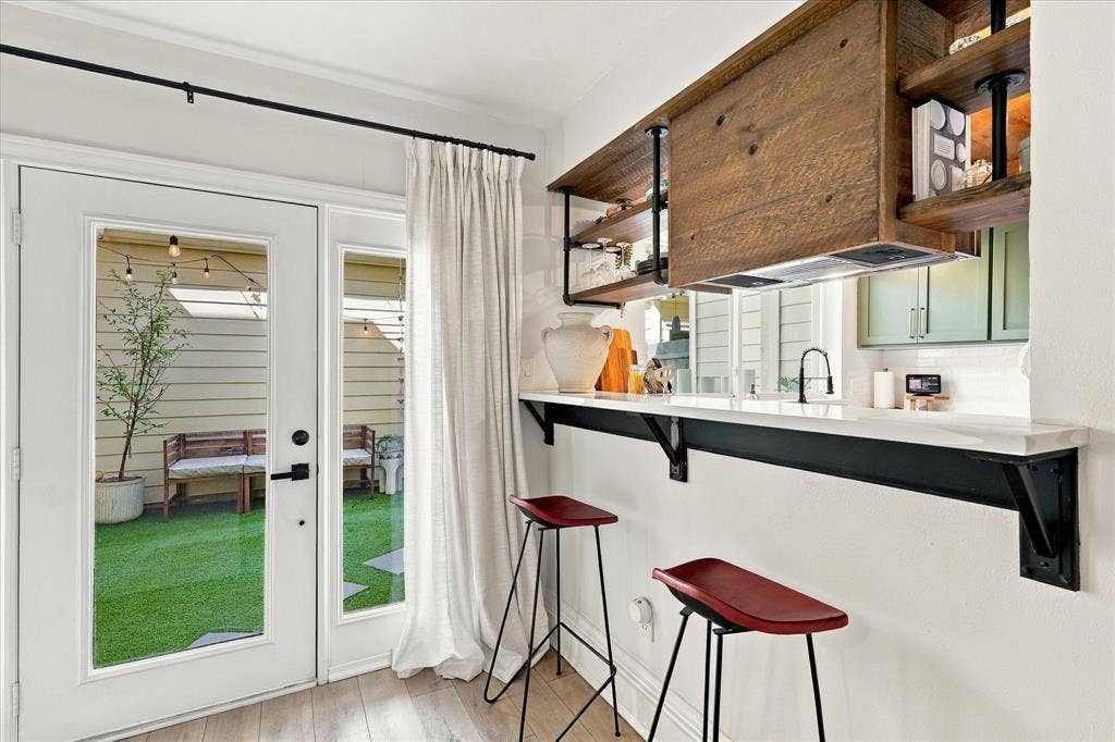 1955 Shorewood Drive, Grapevine, TX 76051 Built-in counter with industrial-style black brackets, wood-finish shelving with integrated plumbing-pipe accents, and glass-paneled exterior door