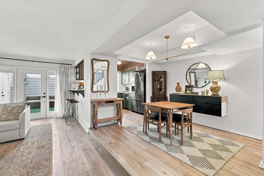1955 Shorewood Drive, Grapevine, TX 76051 Dining area featuring a tray ceiling with a multi-light chandelier, wood-finish flooring, and a glass-paned door providing external access