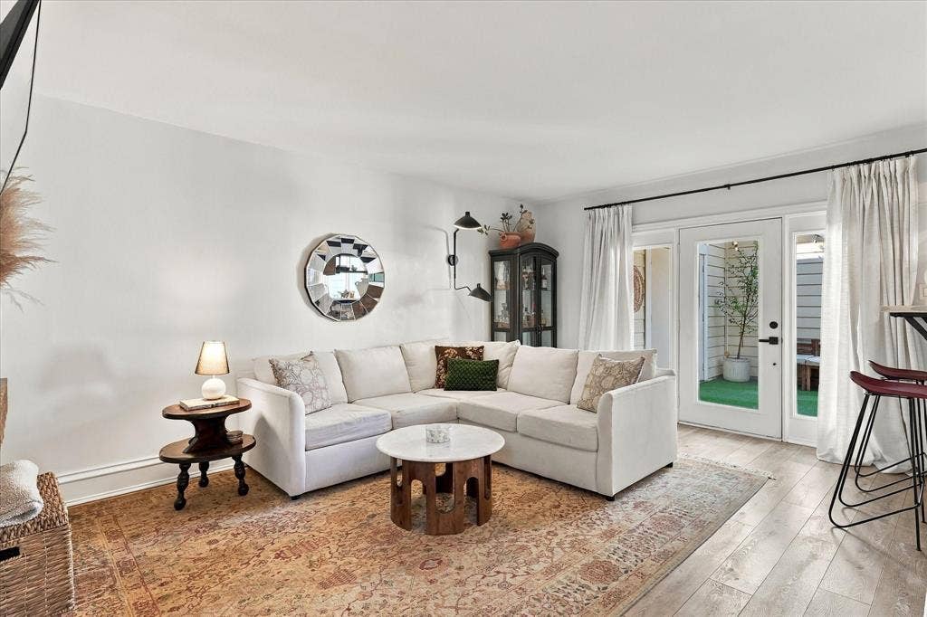1955 Shorewood Drive, Grapevine, TX 76051 Living area featuring wood-finish flooring, dual-arm wall-mounted lighting, and glass-paneled exterior doors with access to an outdoor space