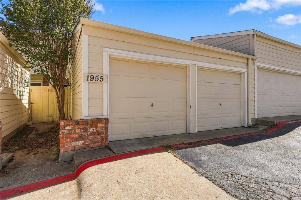1955 Shorewood Drive, Grapevine, TX 76051 Two-car garage featuring horizontal siding, double sectional doors, and decorative brick masonry accents