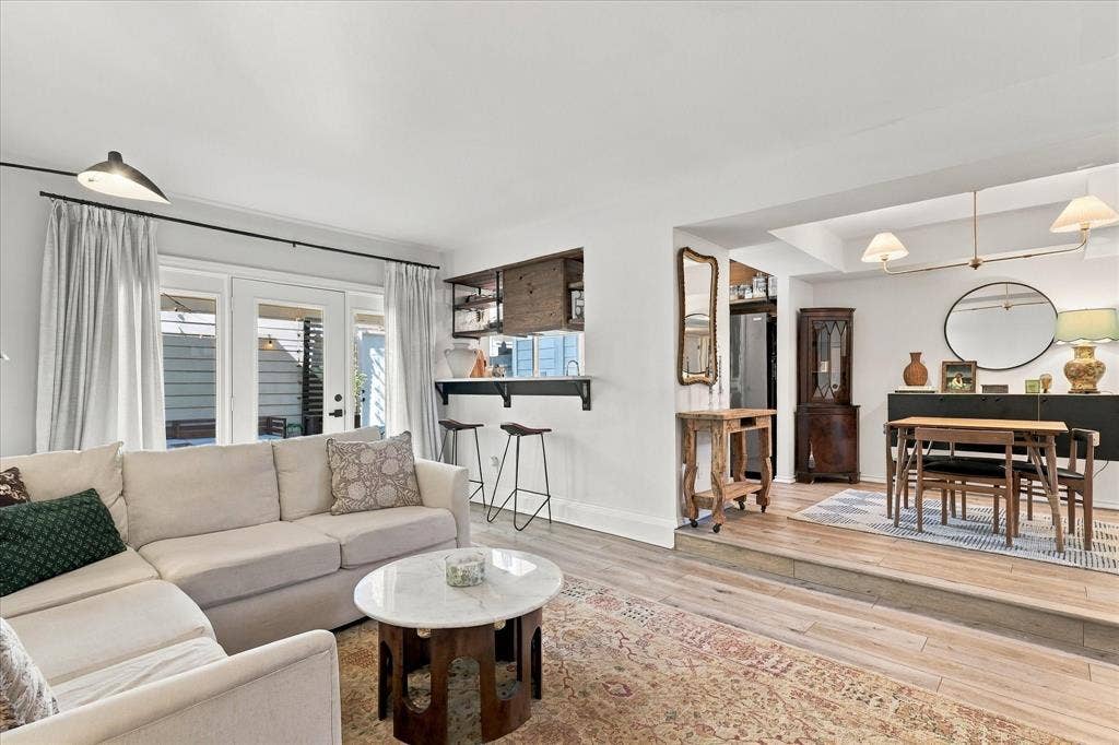1955 Shorewood Drive, Grapevine, TX 76051 Living area featuring wood-finish flooring, a pass-through bar with built-in cabinetry, dual glass-paned doors, and a multi-level floor plan with a raised dining area