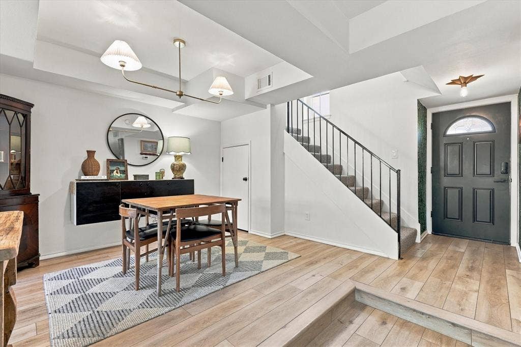1955 Shorewood Drive, Grapevine, TX 76051 Entry featuring wood-finish flooring, recessed tray ceiling, multi-arm metallic light fixture, and a staircase with a black metal railing