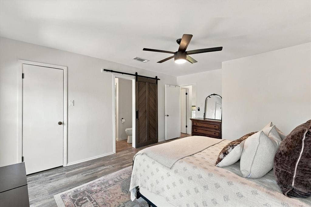 1955 Shorewood Drive, Grapevine, TX 76051 Room featuring wood-finish flooring, a herringbone-pattern sliding barn door, and a multi-blade ceiling fan with integrated lighting