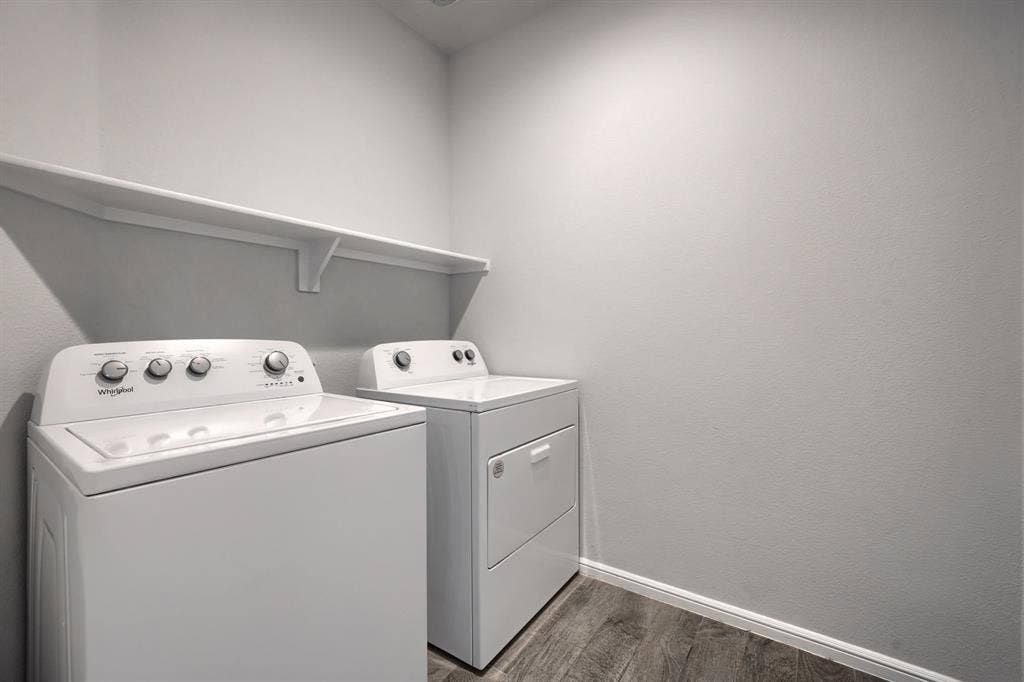 Laundry area featuring wood-finish flooring and a built-in wall-mounted shelf