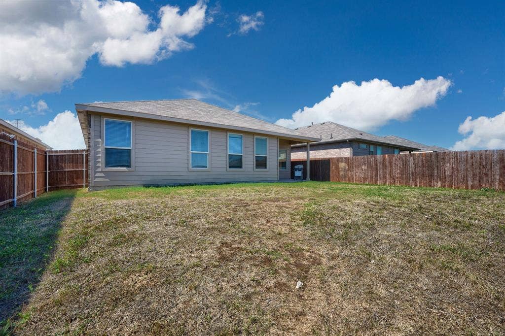 Rear exterior featuring horizontal lap siding, a hipped roofline, inset covered patio, and wood privacy fencing