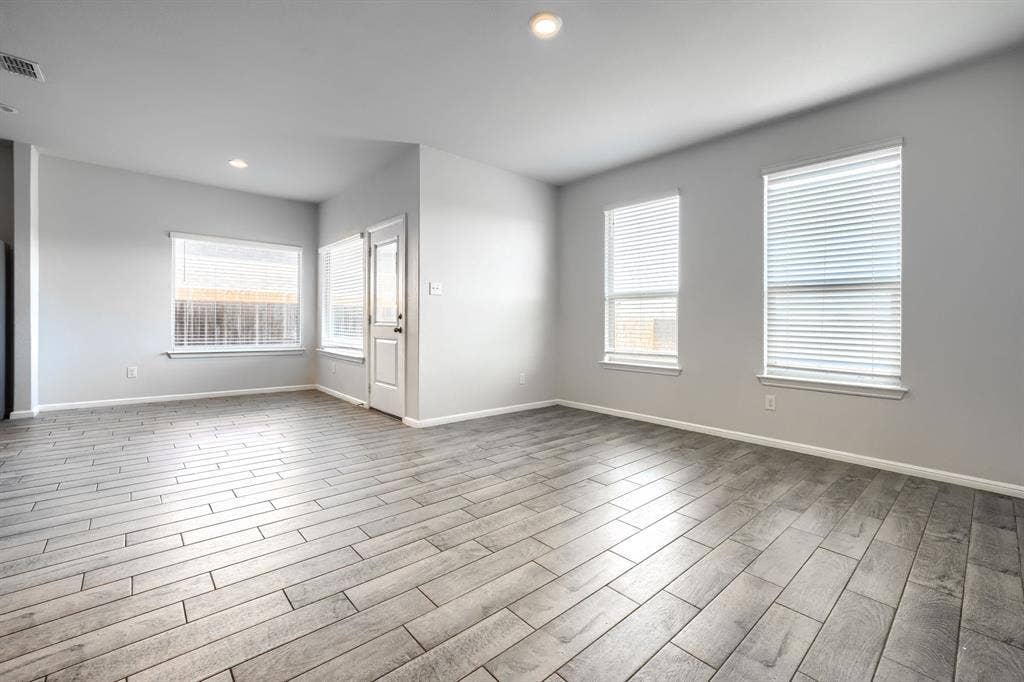 Neutral-toned interior featuring wood-finish flooring, recessed lighting, and multiple windows with installed blinds