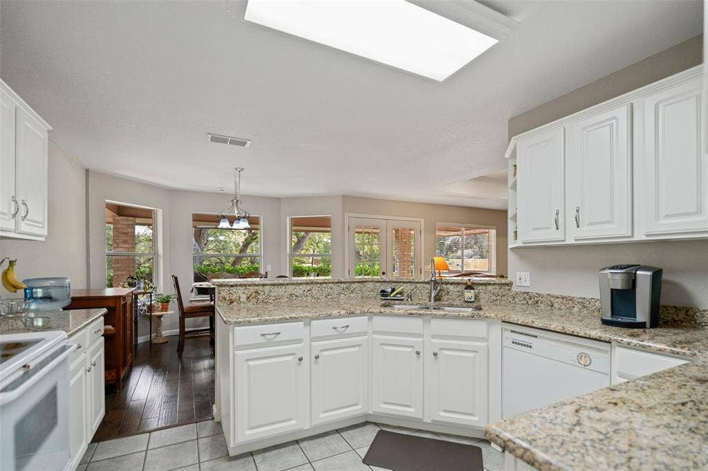 511 Casas Del Norte Court, Granbury, TX 76049 Kitchen featuring white cabinetry, granite countertops, double-basin stainless steel sink, and tile flooring