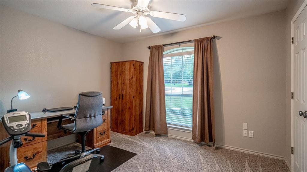 511 Casas Del Norte Court, Granbury, TX 76049 3rd bedroom being utilized at office featuring a central ceiling fan with an integrated light fixture, carpeted flooring, and an arched window