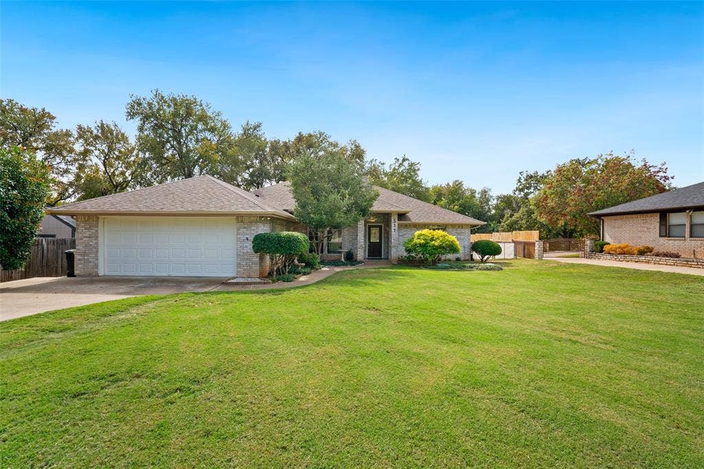 511 Casas Del Norte Court, Granbury, TX 76049 Single-story brick exterior featuring an attached two-car garage, and a manicured front lawn with mature landscaping