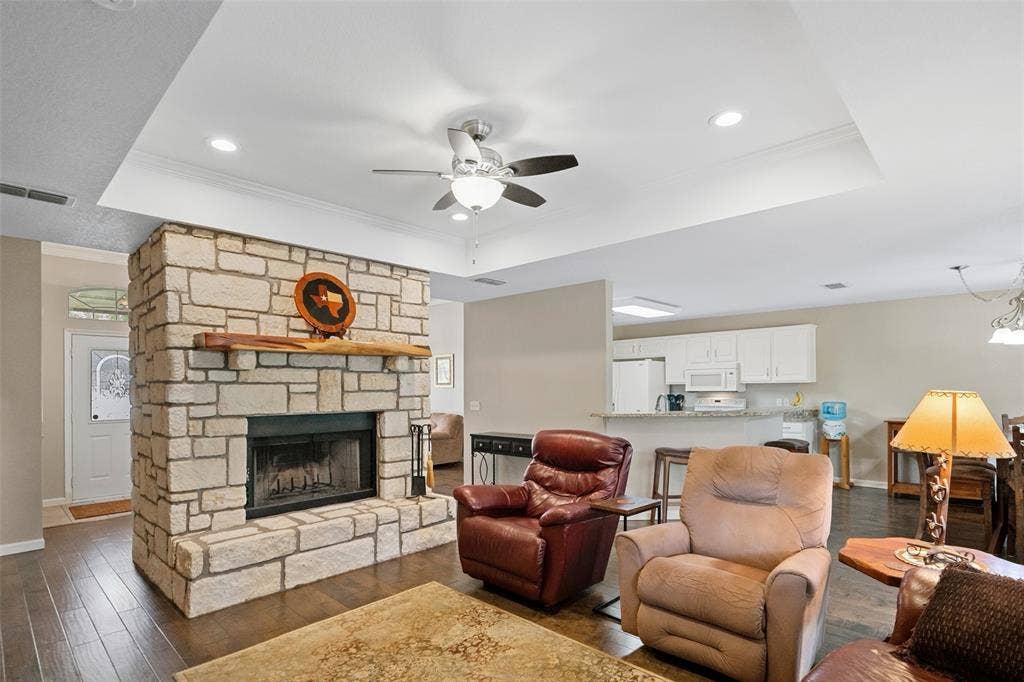 511 Casas Del Norte Court, Granbury, TX 76049 Living area featuring a floor-to-ceiling natural stone fireplace, a natural wood mantel, wood-finish flooring, a tray ceiling, and recessed lighting